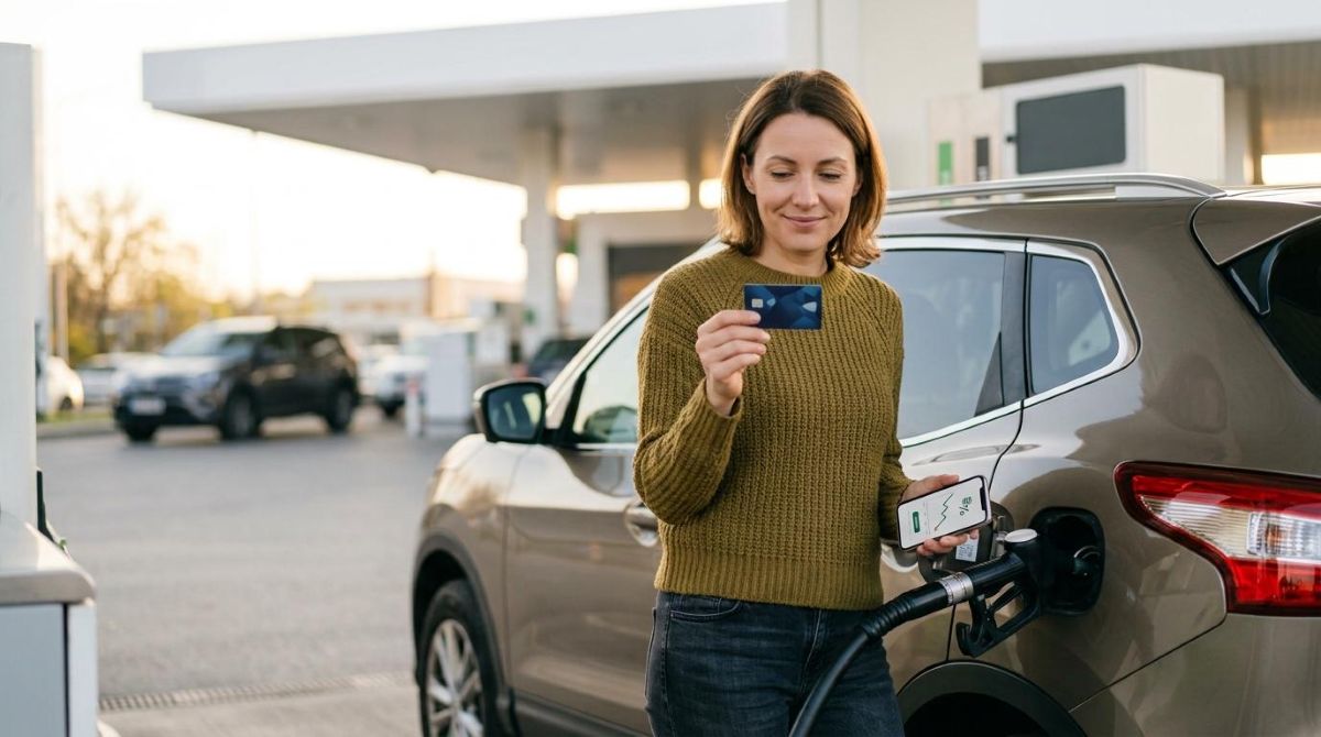 Como economizar em combustível usando cartão de crédito: estratégias que vão além do cashback 3 Pessoa segurando cartão e celular enquanto abastece carro em posto de gasolina ao ar livre